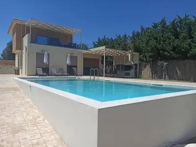 a swimming pool in front of a house at Villa Dedalos in Kalamitsi Amygdali