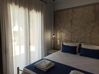 a bedroom with a bed with blue pillows and a window at Villa Dedalos in Kalamitsi Amygdali