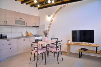a kitchen with a table and chairs and a tv at VAMA APARTMENT in Plataniás