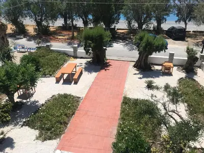 a brick pathway with benches and tables in a park at Zorbas in Sougia