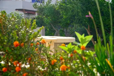 a stone table in a garden with orange flowers at Mpoulakis Apt 46 in Kissamos