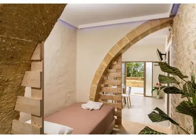 a room with a bed and a spiral staircase at Poseidon Apartments in Kissamos