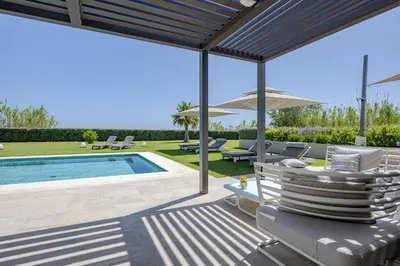 a patio with a pool and chairs and an umbrella at Iniada Villas in Chania Town