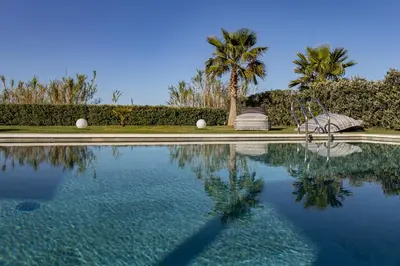 a swimming pool with a swing and a palm tree at Iniada Villas in Chania Town