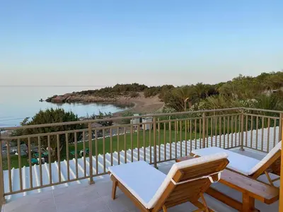 a balcony with two chairs and a view of the ocean at Houmas Apartments in Yialós