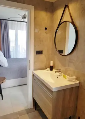 a bathroom with a sink and a mirror and a bed at Houmas Apartments in Yialós