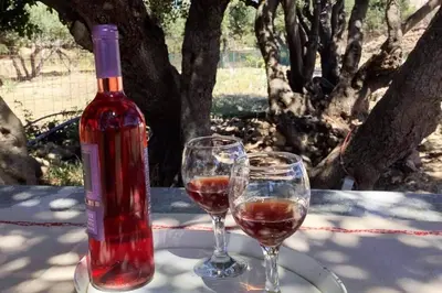 a bottle of wine and two glasses on a table at Haroupia in Elafonisi