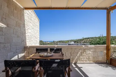 a patio with a wooden table and chairs on a stone wall at Belair villas in Chania Town