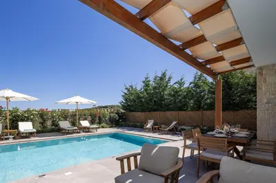 a swimming pool with a table and chairs next to a house at Belair villas in Chania Town