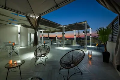 a rooftop patio with chairs and tables and lights at xSuites - Adults Only Boutique Suites with Private Jacuzzi in Agia Marina Nea Kydonias