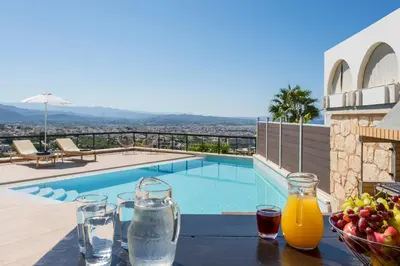 a table with drinks and a bowl of fruit next to a swimming pool at Villa City View - Heated Pool & Gym - Majestic views - 5 min drive from center in Chania Town