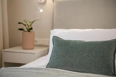 a bed with a pillow and a plant on a night stand at Margiani Studio & Apartment in Chania Town