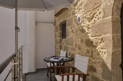 a patio with a table and chairs and an umbrella at Studio Batilas in Kaláthenai