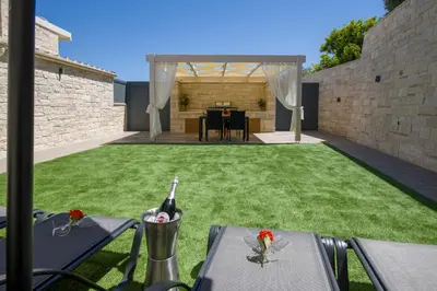 a patio with a lawn with a table with a bottle of wine at TWIN'S HOME LUXURY SUITES in Alikianós