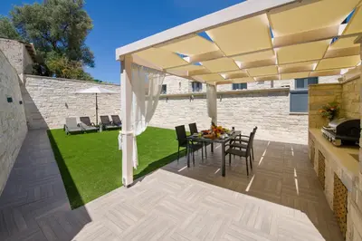 a patio with a yellow umbrella and a table and chairs at TWIN'S HOME LUXURY SUITES in Alikianós