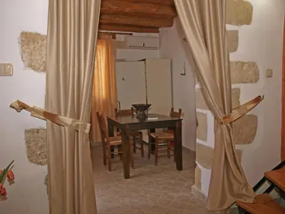 a dining room with a table and a room with a curtain at Vafes Traditional Stone Houses in Vafés