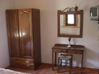 a bedroom with a wooden dresser and a mirror at Patriko Traditional Stone Houses in Vafés