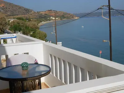 a table on a balcony with a view of the water at Kalyves Bay in Kalyves