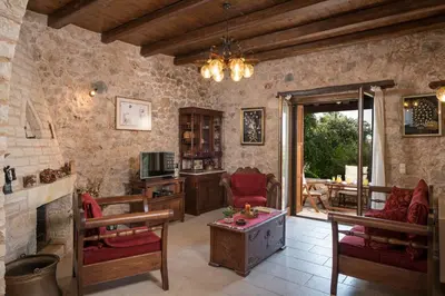 a living room with a fireplace and red chairs at Xatheri Villas in Vamos