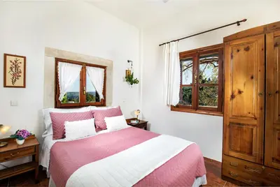 a bedroom with a pink and white bed and windows at Villa Zoi Tzitzifes in Tzitzifés