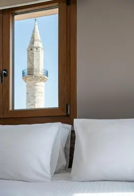 a bedroom with a view of a lighthouse through a window at Al Daliani Minaret Rooms in Chania Town