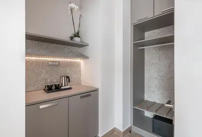 a kitchen with white cabinets and a wall with shelves at Al Daliani Minaret Rooms in Chania Town