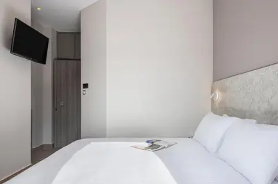 a bedroom with a white bed and a television at Al Daliani Minaret Rooms in Chania Town