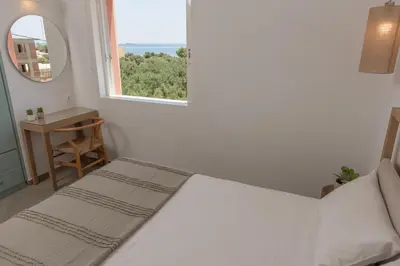 a white bedroom with a bed and a window at Eden of grameno Luxury sea view apartment in Palaiochóra