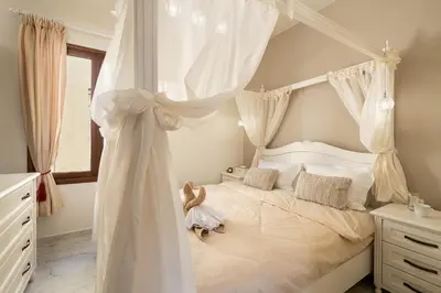 a white bedroom with a canopy bed with curtains at Chrisselen Palazzo Colombo in Chania Town