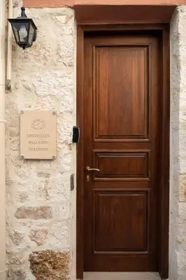 a wooden door on a stone wall with a sign at Chrisselen Palazzo Colombo in Chania Town