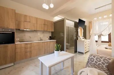 a kitchen with wooden cabinets and a white table in a room at Chrisselen Palazzo Colombo in Chania Town