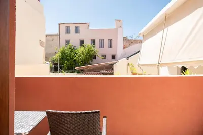 a pair of chairs on a balcony with buildings at Chrisselen Palazzo Colombo in Chania Town