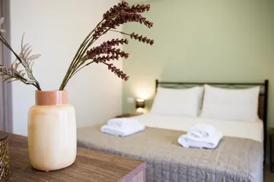 a vase with flowers on a table next to a bed at Gardenia Apartment in Kissamos