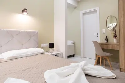 a white bedroom with a bed and a mirror at Gardenia Apartment in Kissamos