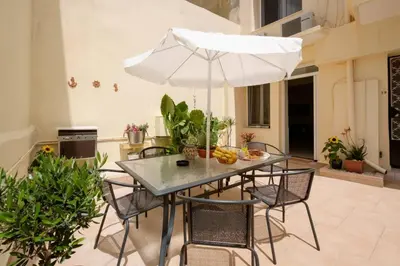 a table with chairs and an umbrella in a room at Family home w. yard in Beating Heart of Old Town in Chania Town