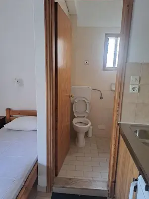 a bathroom with a toilet and a sink and a bed at LITHI in Palaiochóra