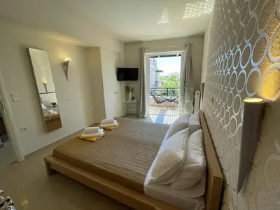 a bedroom with a bed and a large window at Artdeco Luxury Suites in Korakiaí