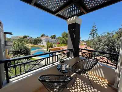 a balcony with two chairs and a view of a pool at Artdeco Luxury Suites in Korakiaí