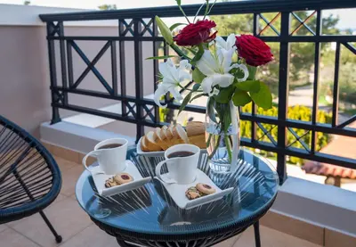 a glass table with a vase of flowers and pastries at Artdeco Luxury Suites in Korakiaí