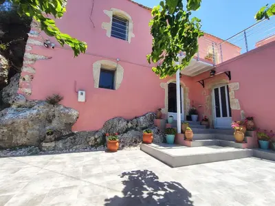 a pink house with potted plants in front of it at Rocky Mountain Villa in Ramní
