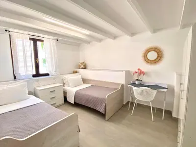 a white bedroom with two beds and a table at PRIMAVERA in Kalamaki Chanion