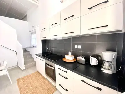 a kitchen with white cabinets and a black counter top at PRIMAVERA in Kalamaki Chanion
