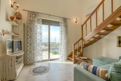 a living room with a blue couch and a sliding glass door at Pink Sand Villas in Agios Padeleimon