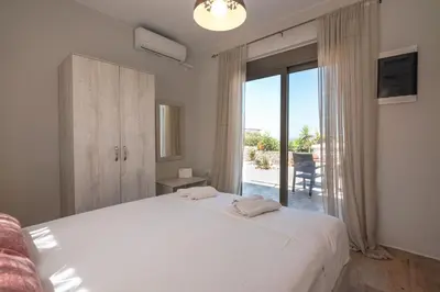 a bedroom with a large white bed and a balcony at Pink Sand Villas in Agios Padeleimon