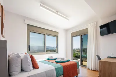 a bedroom with a bed and a tv and windows at Centro Golden View Villa in Chania Town