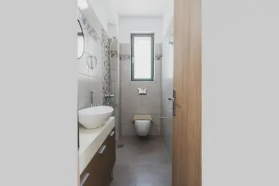 a bathroom with a sink and a toilet and a mirror at Park-view Lux Pool Villa, steps to the Beach in Aghii Apostoli