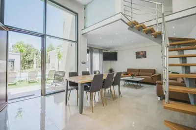 a dining room and living room with a table and chairs at Park-view Lux Pool Villa, steps to the Beach in Aghii Apostoli