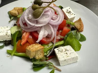 a salad with onions and vegetables on a white plate at Hotel Plakures in Falasarna