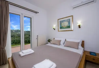 a bedroom with a large bed with a large window at Villa Thallo in Galatás