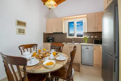 a kitchen with a table and chairs and a refrigerator at Villa Thallo in Galatás